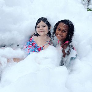 Two young happy girls smiling and playing in foam bubbles during a foam party in Washington DC, Maryland, Virginia.